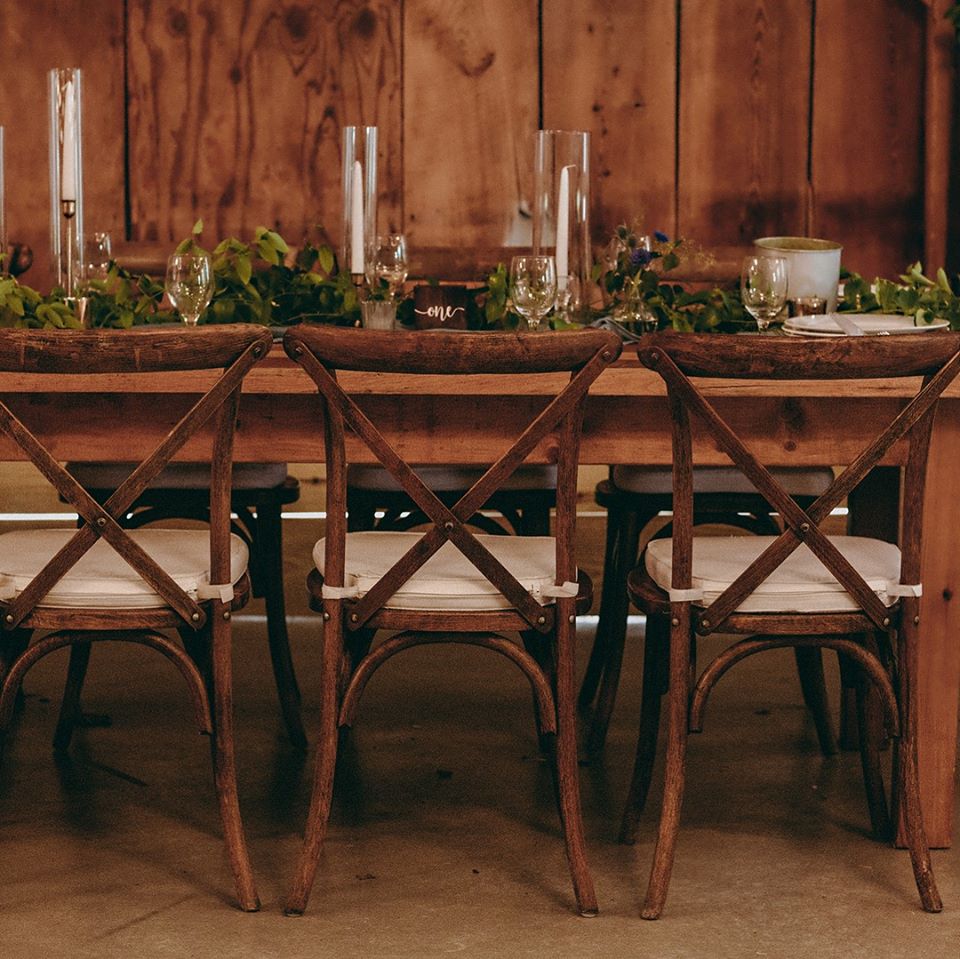cross-back chairs set up at farmhouse tables for a wedding