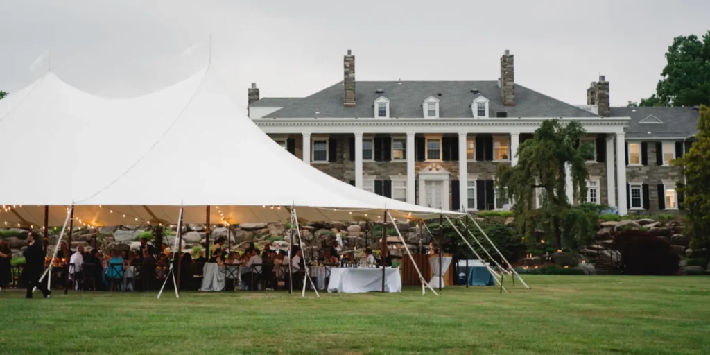 Sailcloth wedding tent set up for an outdoor wedding in front of an estate house.