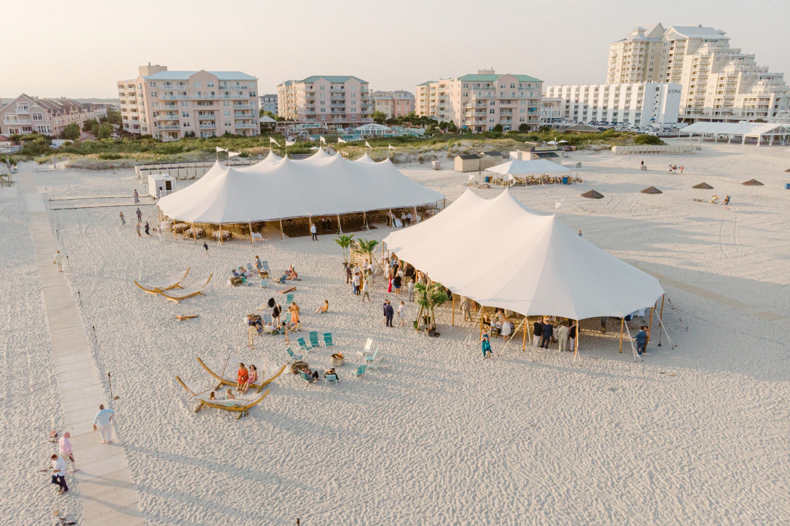 two white tents set up on sandy beach for wedding reception
