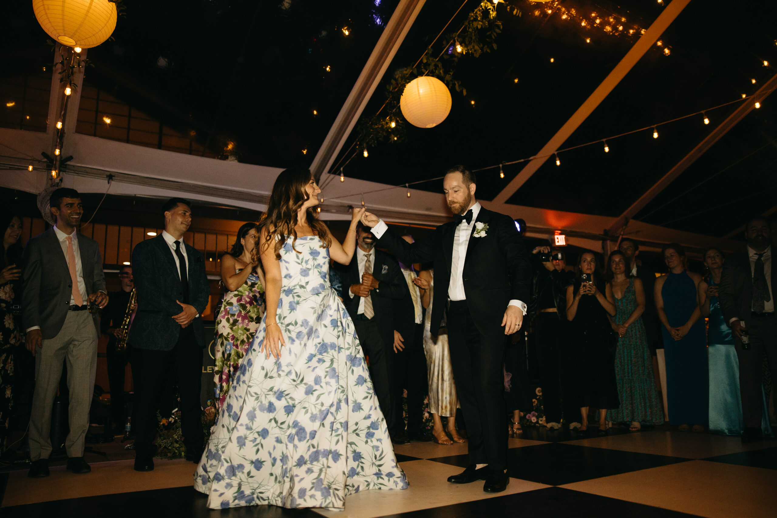 bride wearing blue floral gown, standing with groom under clear tent