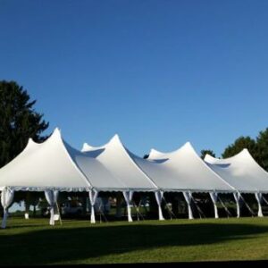 60x120 high peak pole tent with side pole drapes, set up on grass