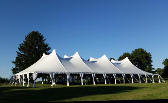 60x120 high peak pole tent with side pole drapes, set up on grass