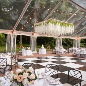 clear top frame tent set up on brick patio, with black and white dance floor and white floral suspended chandelier