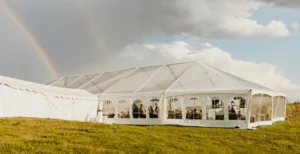 clear top tent with marquee connected to building, rainbow in background