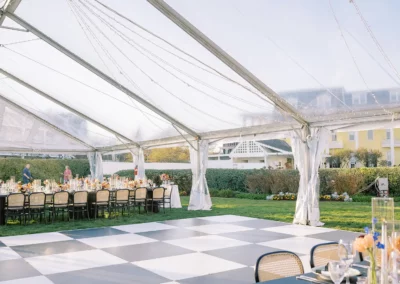 clear tent with black and white dance floor under it. yellow building in background