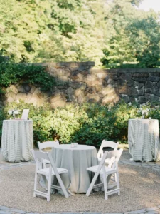 Winterthur during cocktail hour with white padded resin chairs and low top tables surrounded by cocktail tables in a sage striped linen