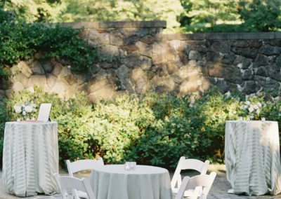 Winterthur during cocktail hour with white padded resin chairs and low top tables surrounded by cocktail tables in a sage striped linen