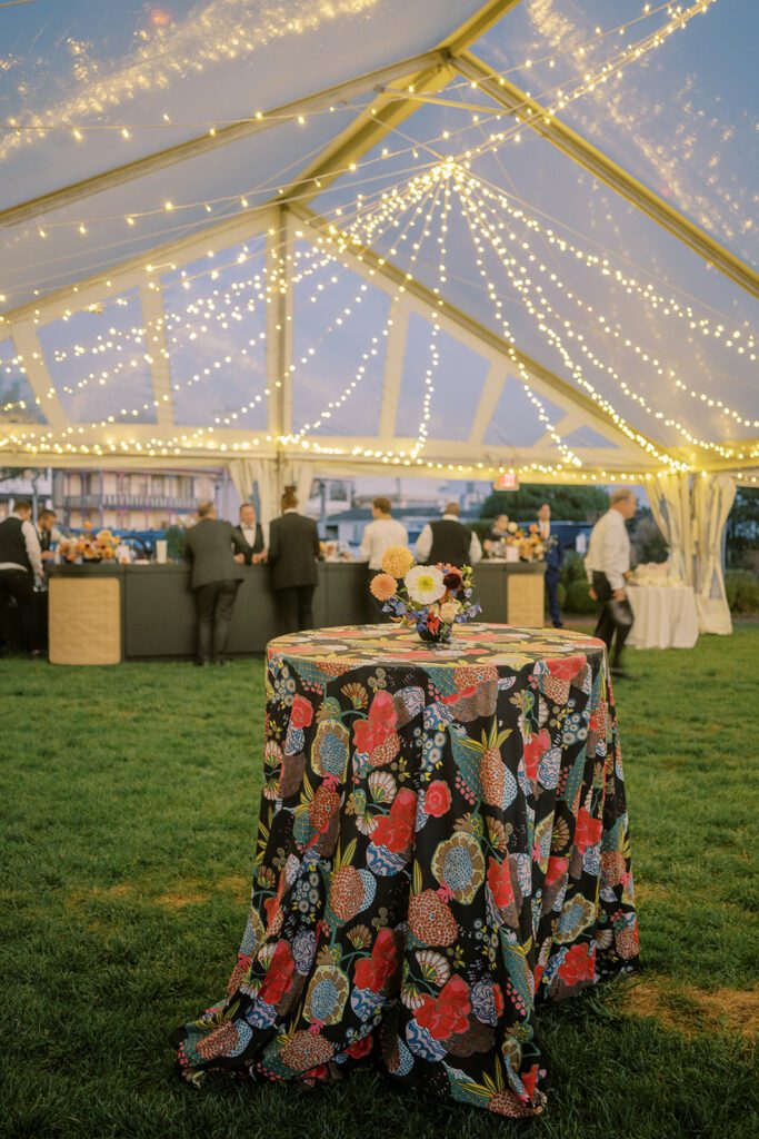 clear top frame wedding tent with draped twinkle lighting and table with floral linen
