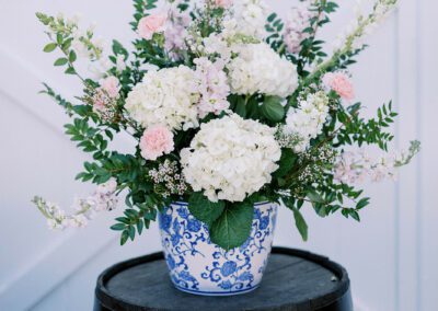 wine barrel with flowers in blue and white vase