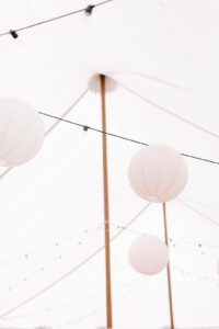 paper lanterns suspended in wedding tent with bistro lighting
