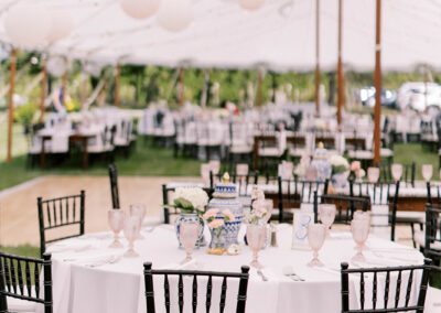 wedding tent with paper lanterns, round tables with white linens, black chairs