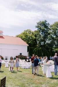 outdoor cocktail hour on grass in front of white barn