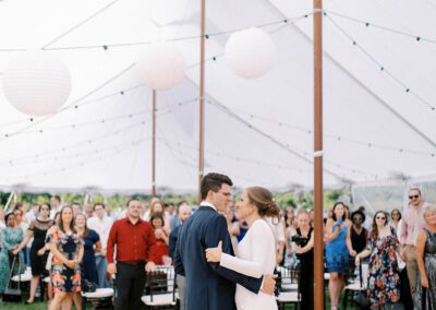 bride and groom dancing under large white tent