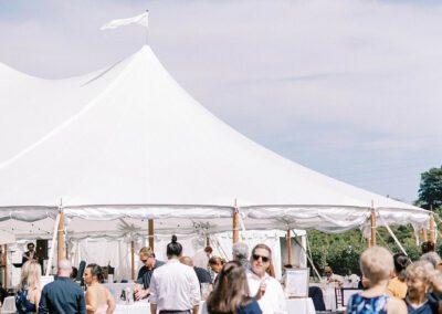 outdoor cocktail hour in grass in front of large wedding tent