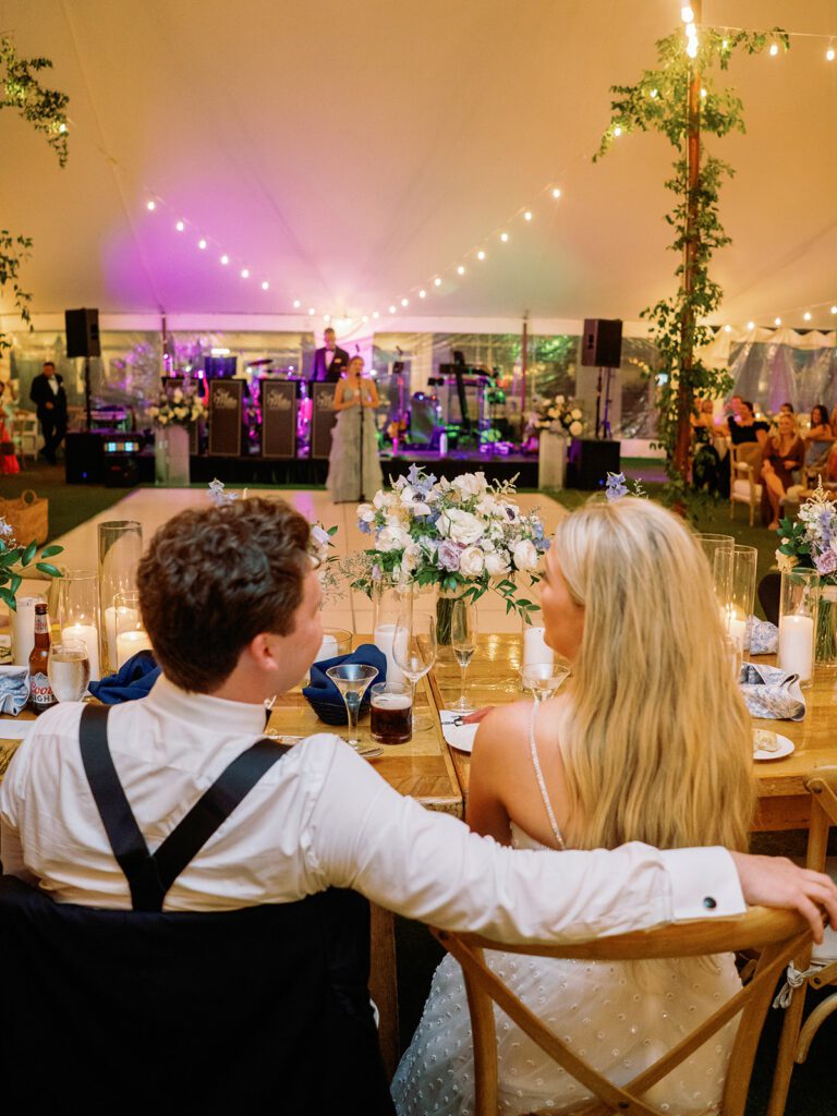 bride and groom seated at head table overlooking their wedding reception