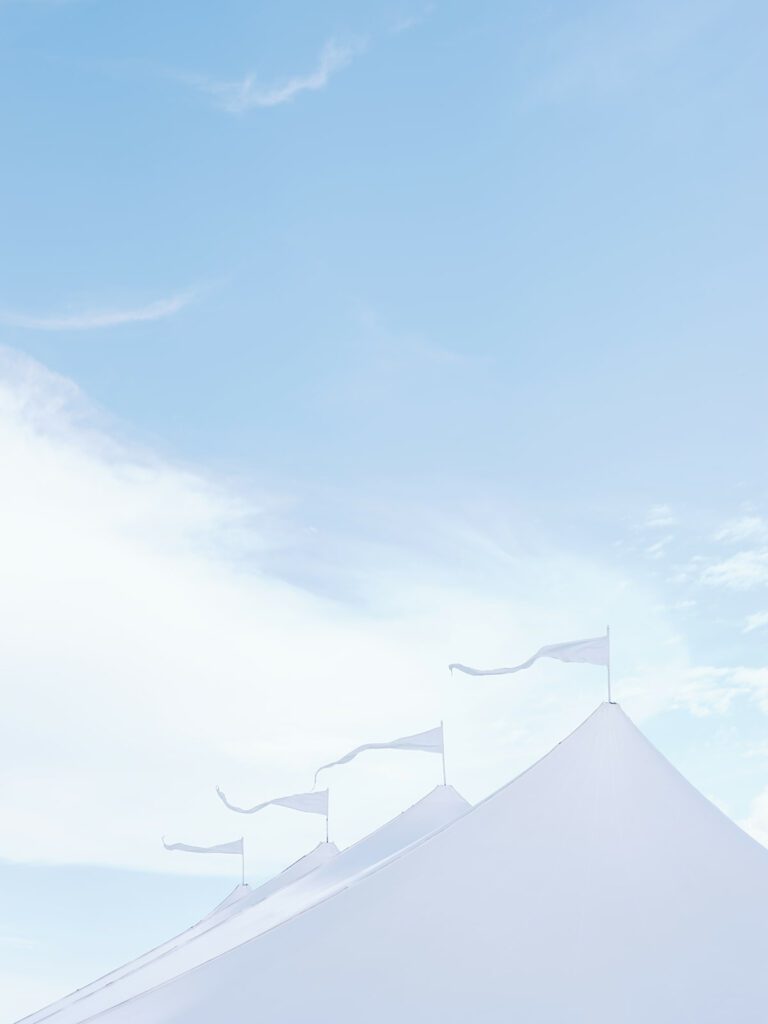 flags on the points of a sailcloth tent flowing in breeze under a blue sky