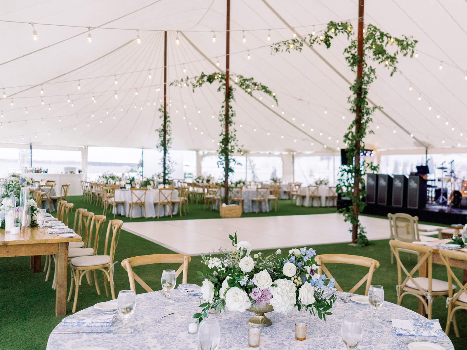 Kelsey + Ben || Rehoboth Beach, DE wedding tent interior showing tables for seating, large dance floor, and greenery wrapped center poles.
