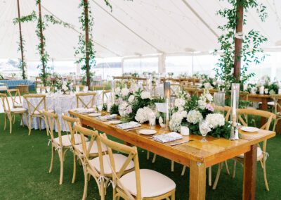 farmhouse table and cross back chairs set up under a white tent for a wedding reception in Delaware.
