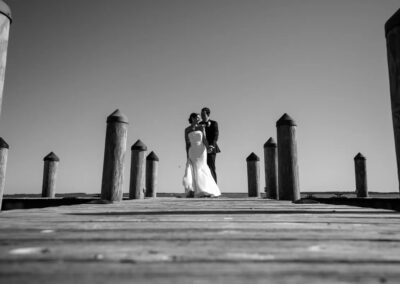 bride and groom standing on dock black and white photo