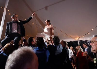 bride and groom held up on chairs celebrating at their wedding reception