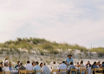guests seated for outdoor dining at long table on sandy beach