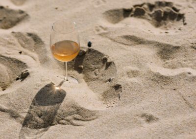 glass of rose wine on sandy beach
