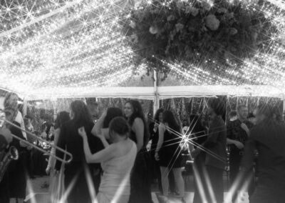 black and white photo of wedding reception under clear top tent with waterfall lighting and floral chandelier