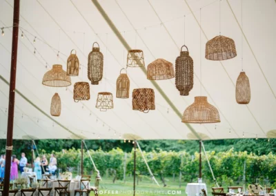 wedding tent with rattan lanterns suspended from ceiling.