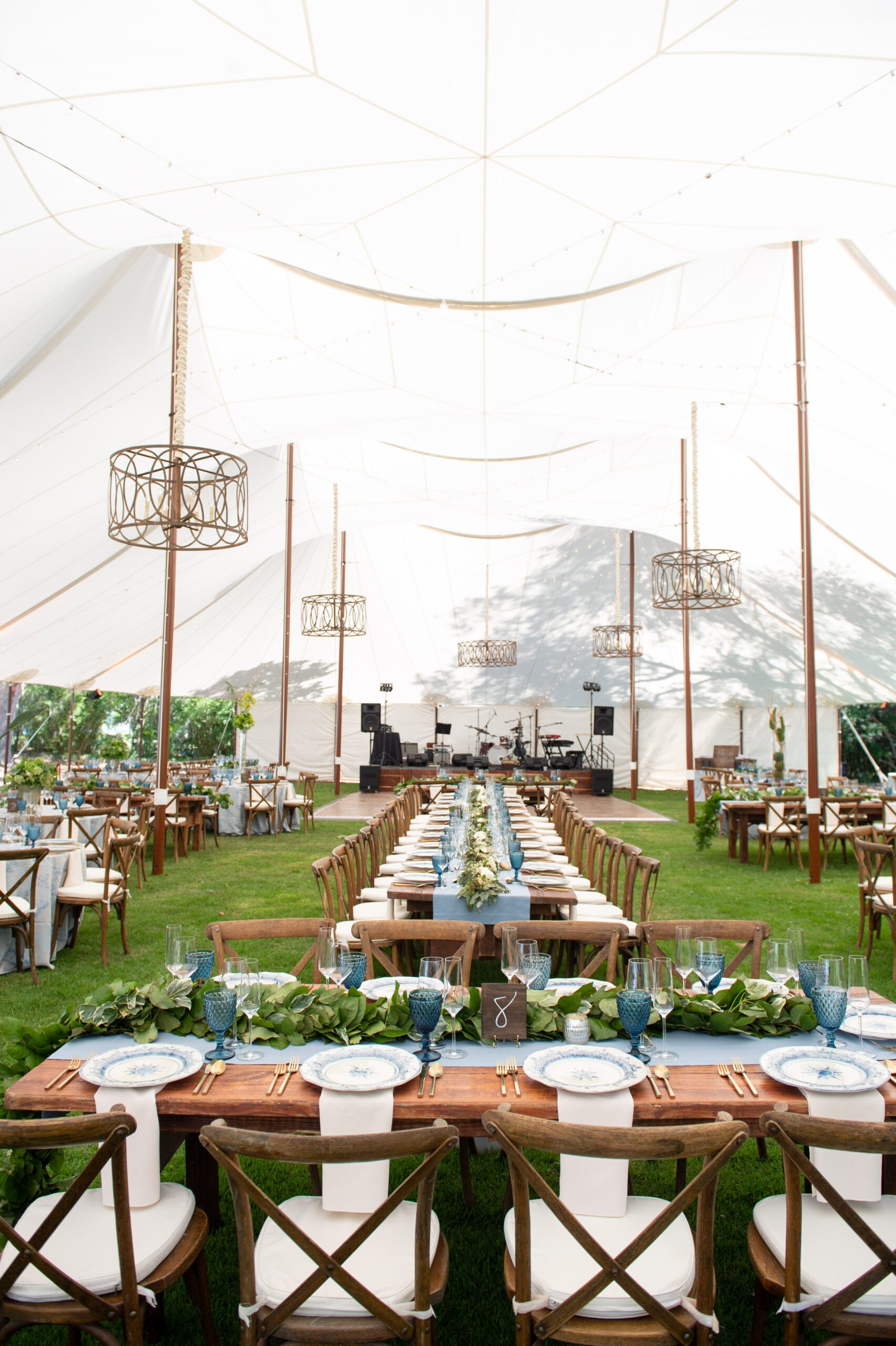 twin pole sailcloth wedding tent set up with farmhouse tables and crossback chairs