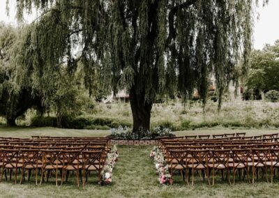 chairs set up for outdoor wedding ceremony in front of willow tree