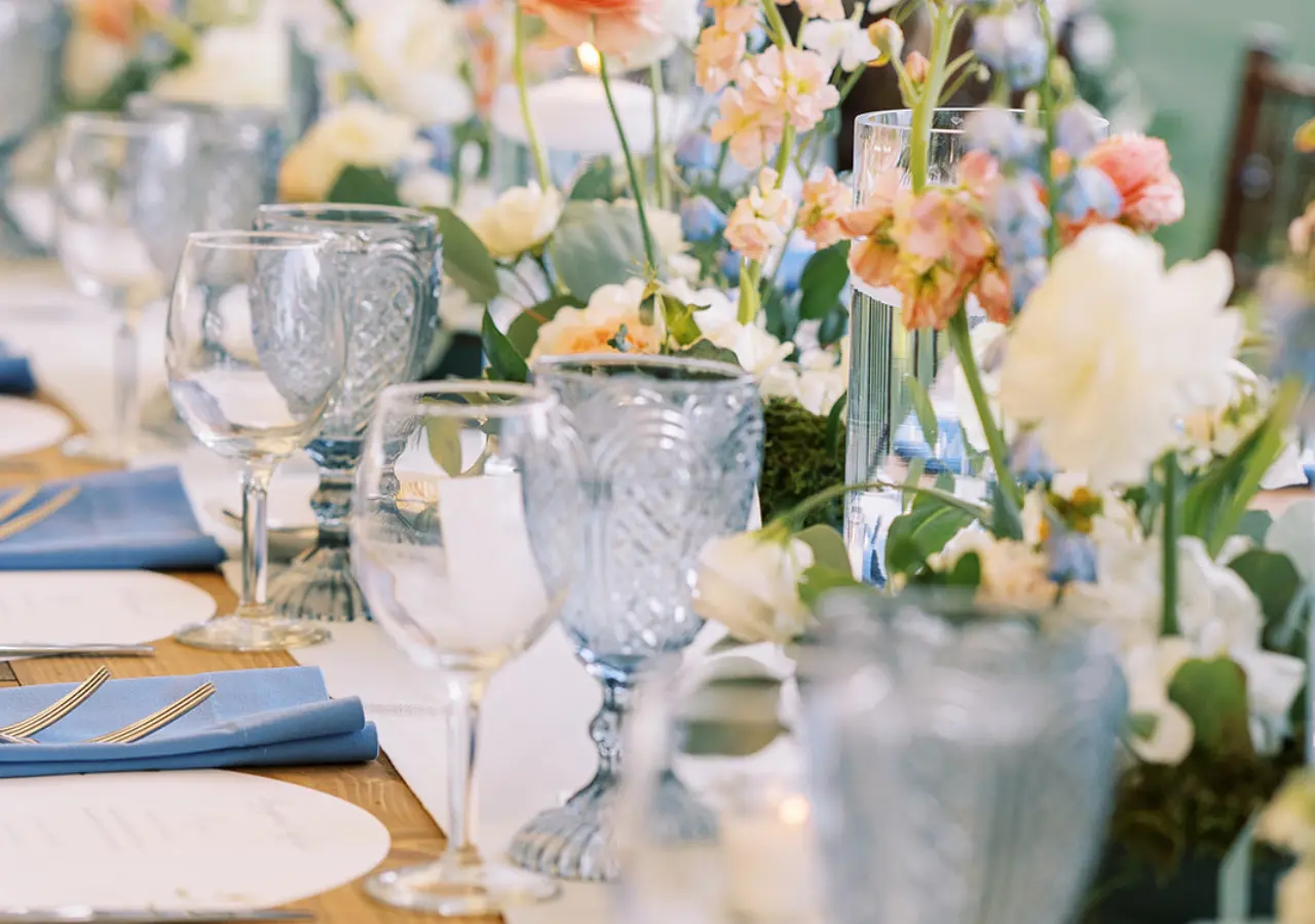 earlyspringwedding_featuredimage Up close view of a reception table with blue goblets, bouncy florals and tablesettings