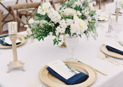 tablescape with white linens, gold charger plates, and navy blue napkins