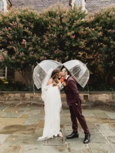 bride and groom kissing under clear umbrellas at winterthur