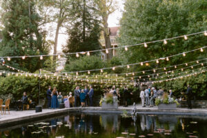 twinkle lighting suspended over reflecting pool with gardens and trees surrounding