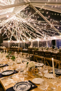 clear top tent set up for a wedding reception with waterfall twinkle lighting suspended throughout
