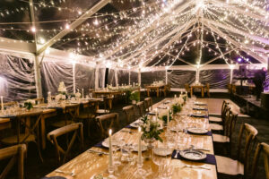 clear top tent set up for a wedding reception with waterfall twinkle lighting suspended throughout