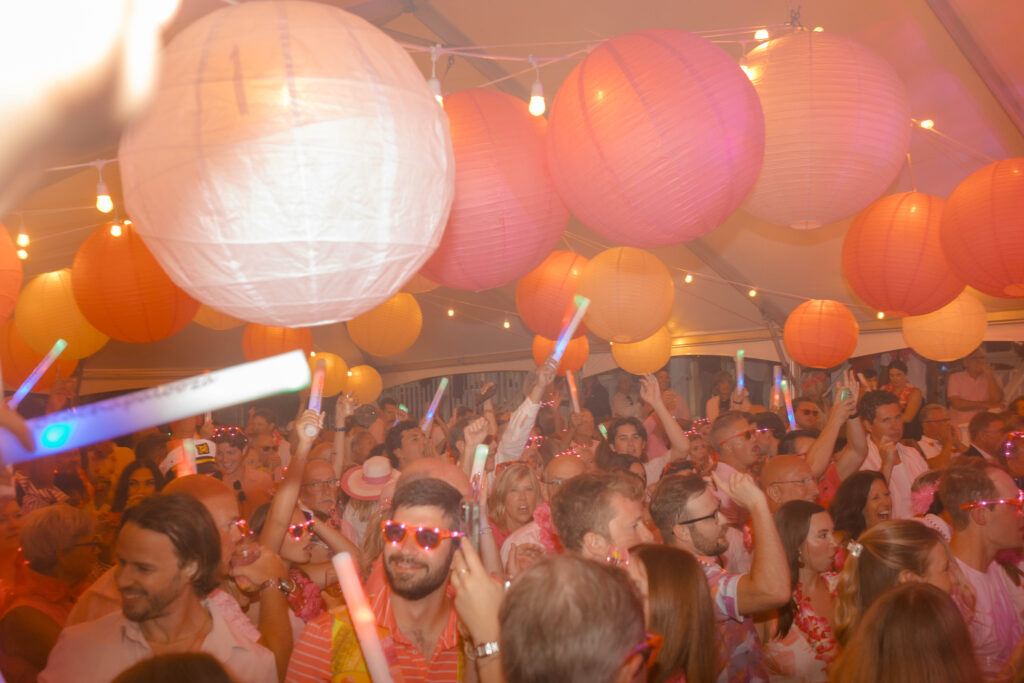 group of people dancing under a tent with pink paper lanterns suspended above