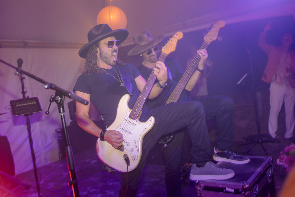 band member playing guitar standing on stage with foot on speaker
