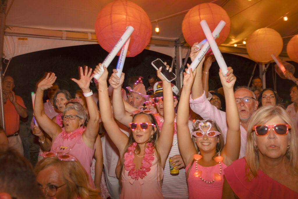 people dancing under a tent with pink paper lanterns suspended above