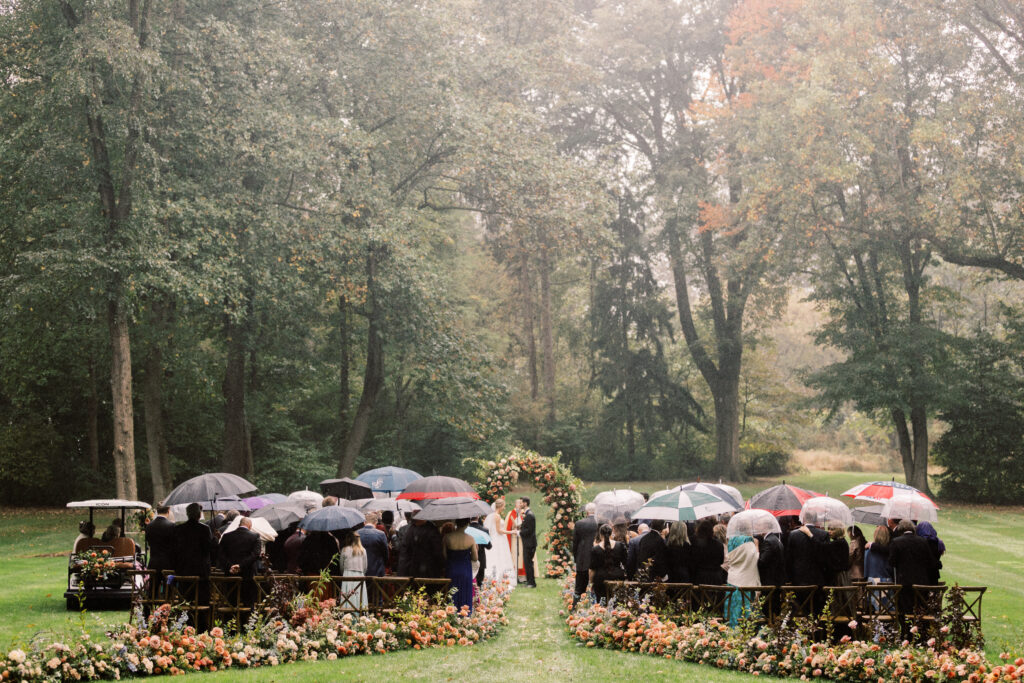 people holding umbrellas for rainy outdoor wedding ceremony