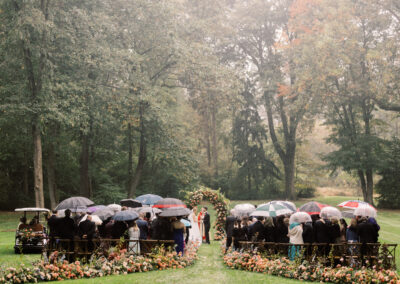 people holding umbrellas for rainy outdoor wedding ceremony