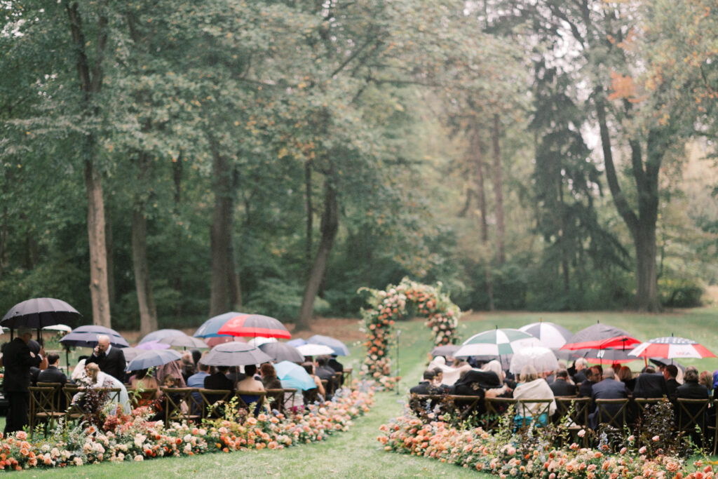 people holding umbrellas for rainy outdoor wedding ceremony