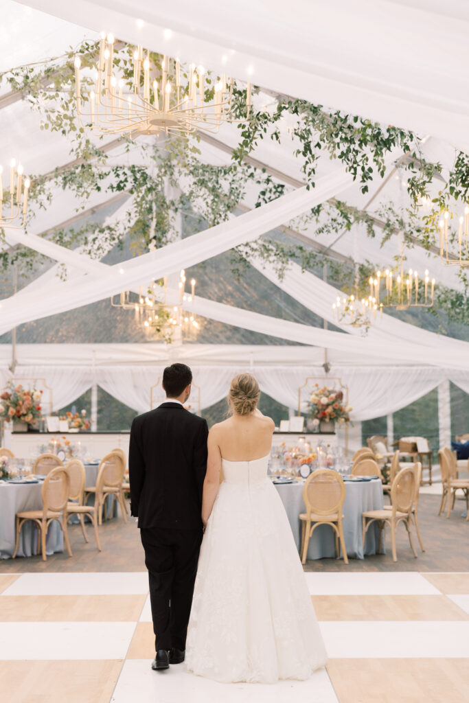 bride and groom standing under their wedding tent