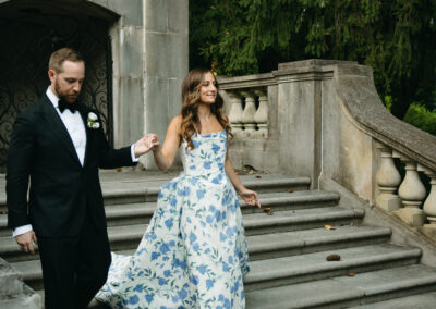bride wearing blue floral wedding gown walking down steps with groom