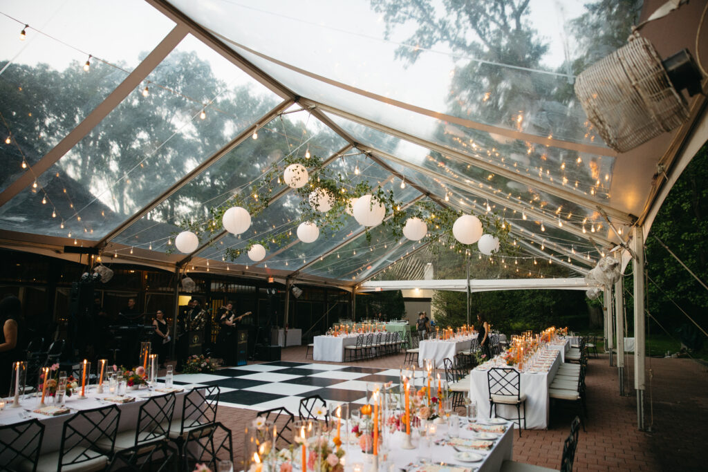 clear top tent with greenery and paper lanterns over black and white dance floor
