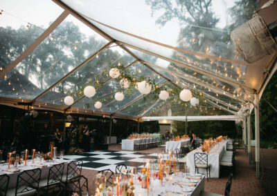 clear top tent with greenery and paper lanterns over black and white dance floor