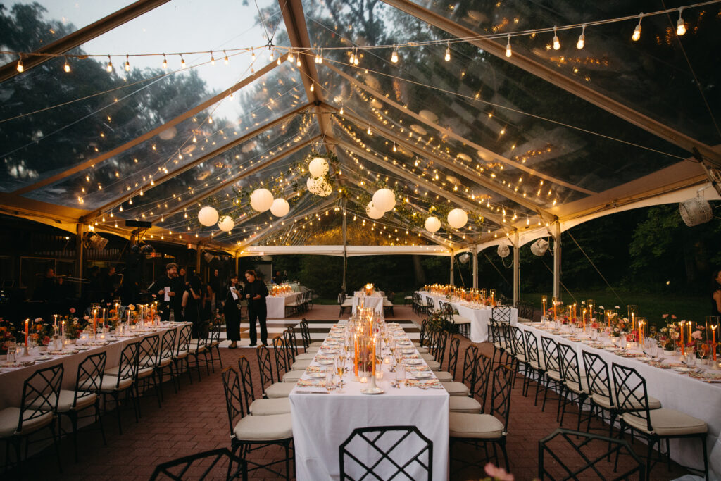 clear top tent with greenery twinkle lighting and paper lanterns