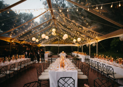 clear top tent with greenery twinkle lighting and paper lanterns