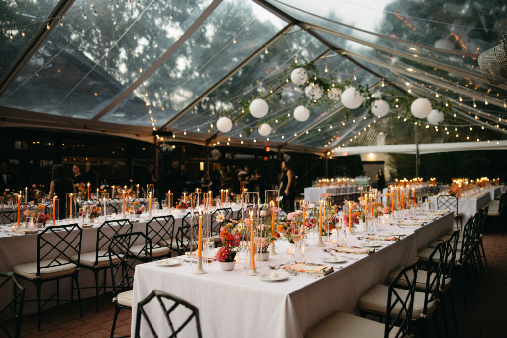 clear top tent with greenery and paper lanterns over tables and chairs