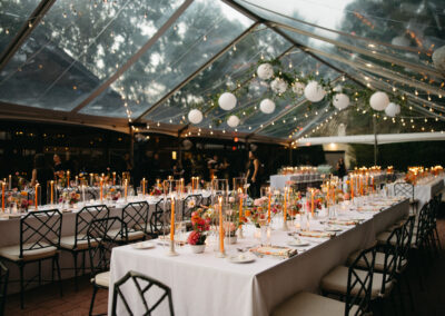 clear top tent with greenery and paper lanterns over tables and chairs